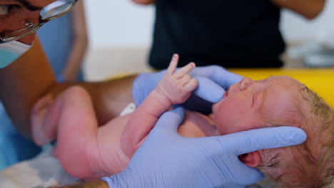 doctor's hands in latex gloves open the newborn's mouth. child examination after birth. close up.