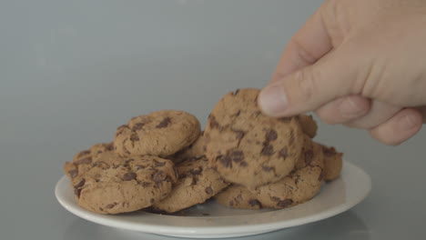 hand placing chocolate chip cookies on pile of cookies - wide