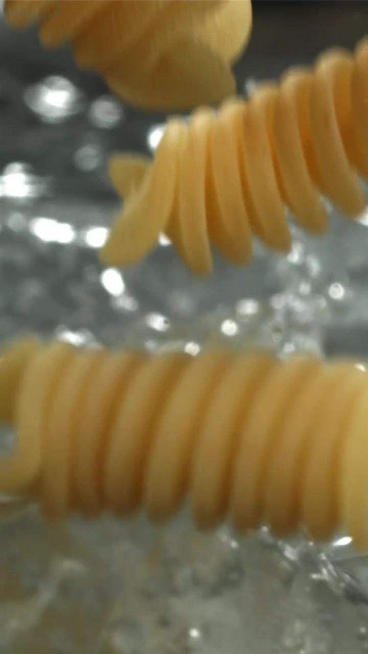 Slow Motion Close-Up of Fusilli Pasta Falling into Boiling Water