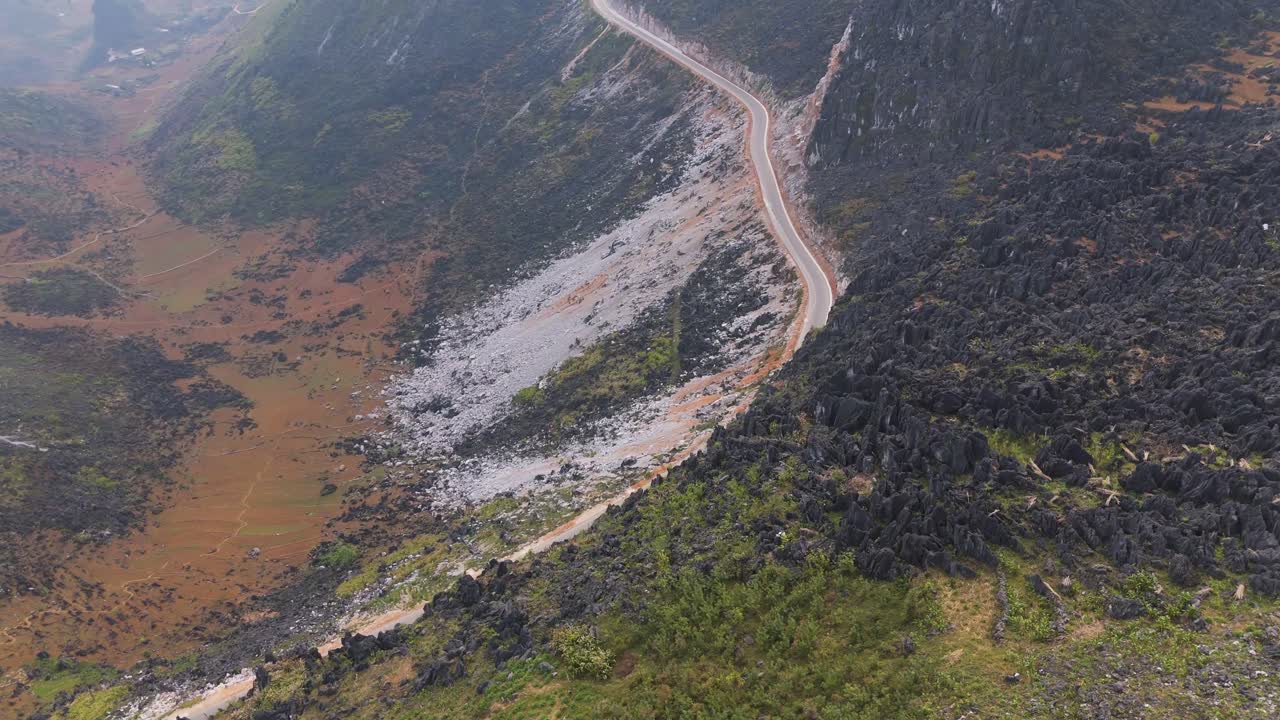 Aerial View of Winding Mountain Road Through Rugged Landscape