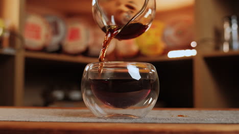 vertiendo té en una taza de té de vidrio