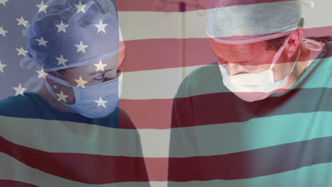 animation of waving usa flag over diverse male and female surgeons performing operation at hospital