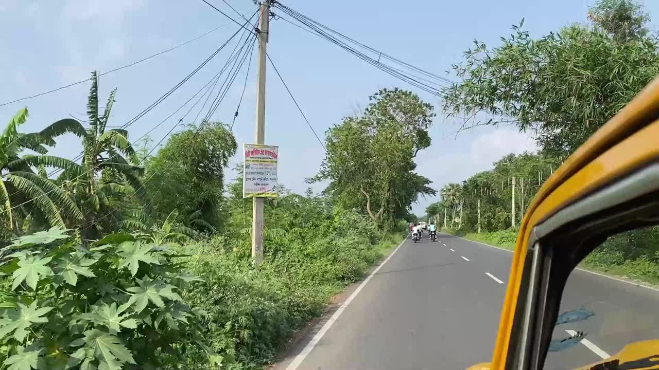 POV shot of a yellow taxi travelling through highway connecting Bengal rural villages