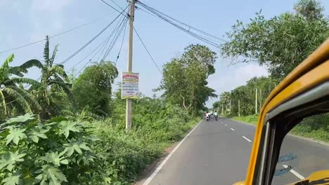 POV-shot-of-a-yellow-taxi-travelling-through-highway-connecting-Bengal-rural-villages