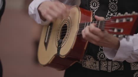 close up of person's hand playing guitar in mariachi band in slow motion