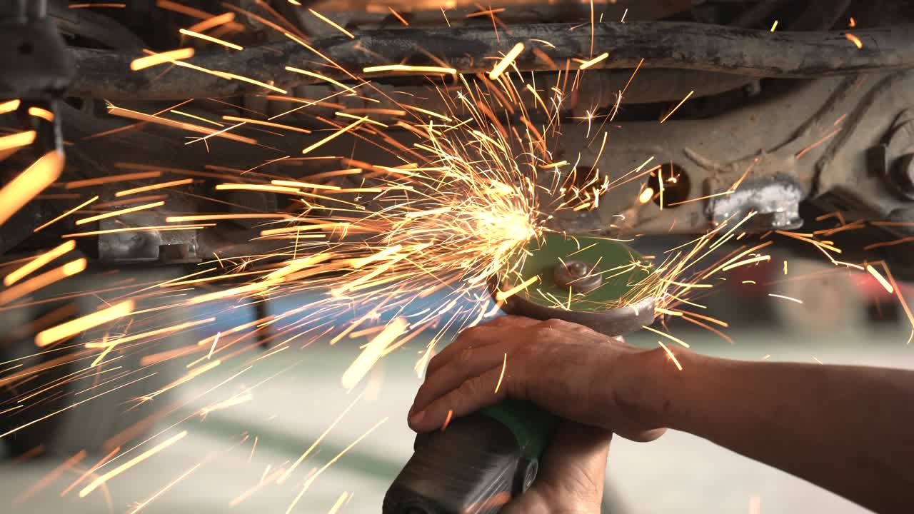 trabajador metalúrgico moliendo en un taller de reparación de carrocerías de automóviles, primer plano