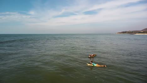 Beautiful-women-prepare-to-surf-near-Vietnam-coastline,-aerial-orbit-view