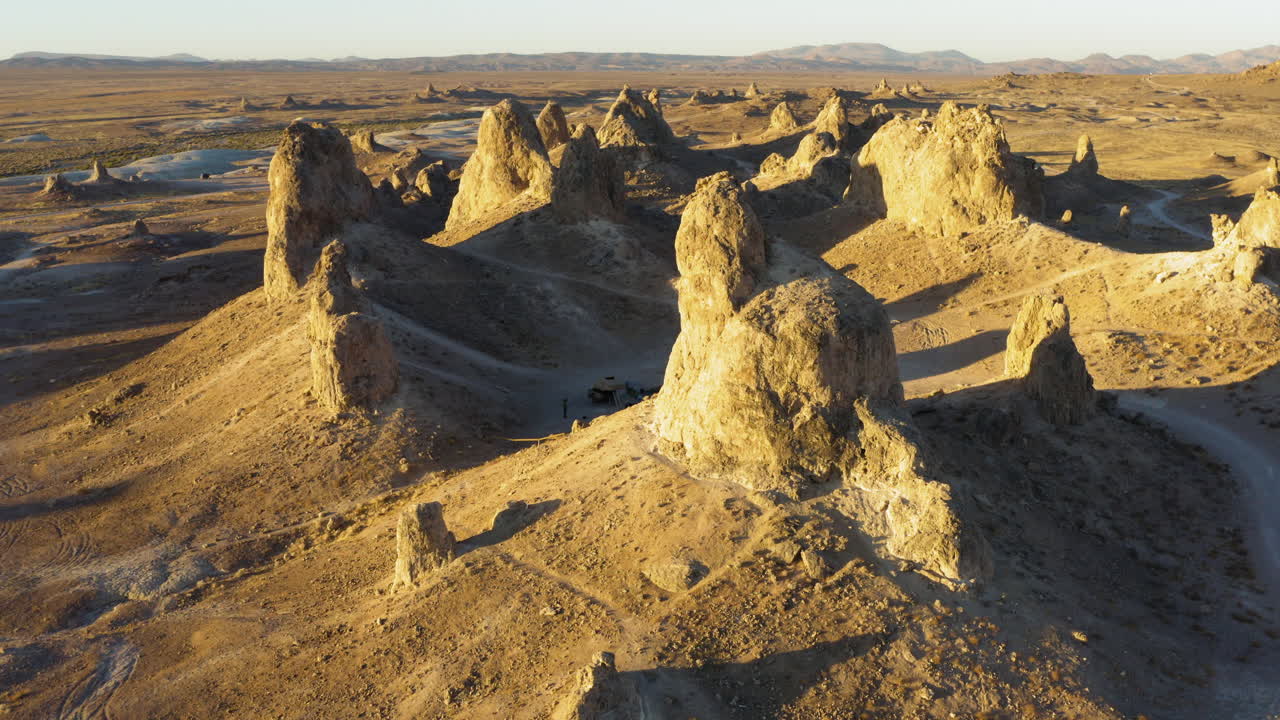 vista aérea mirando hacia abajo a los pináculos de trona en el desierto de mojave durante una puesta de sol de color amarillo brillante