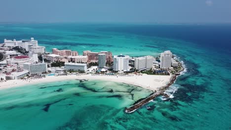 Cancun-coastline-with-clear-blue-waters-and-bustling-beachfront,-aerial-view