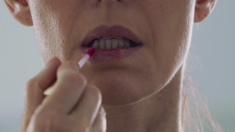 close up, middle aged brunette woman applying lipstick in slow motion