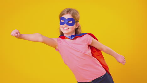 studio portrait of girl dressed as comic book superhero against yellow background