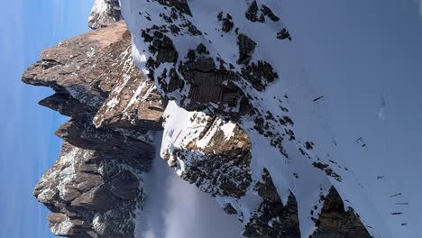 Stunning-vertical-shot-of-snow-covered-Seceda-Mountains-in-Dolomites,-Ortisei,-with-clear-blue-winter-sky,-perfect-for-winter-sports-and-adventure