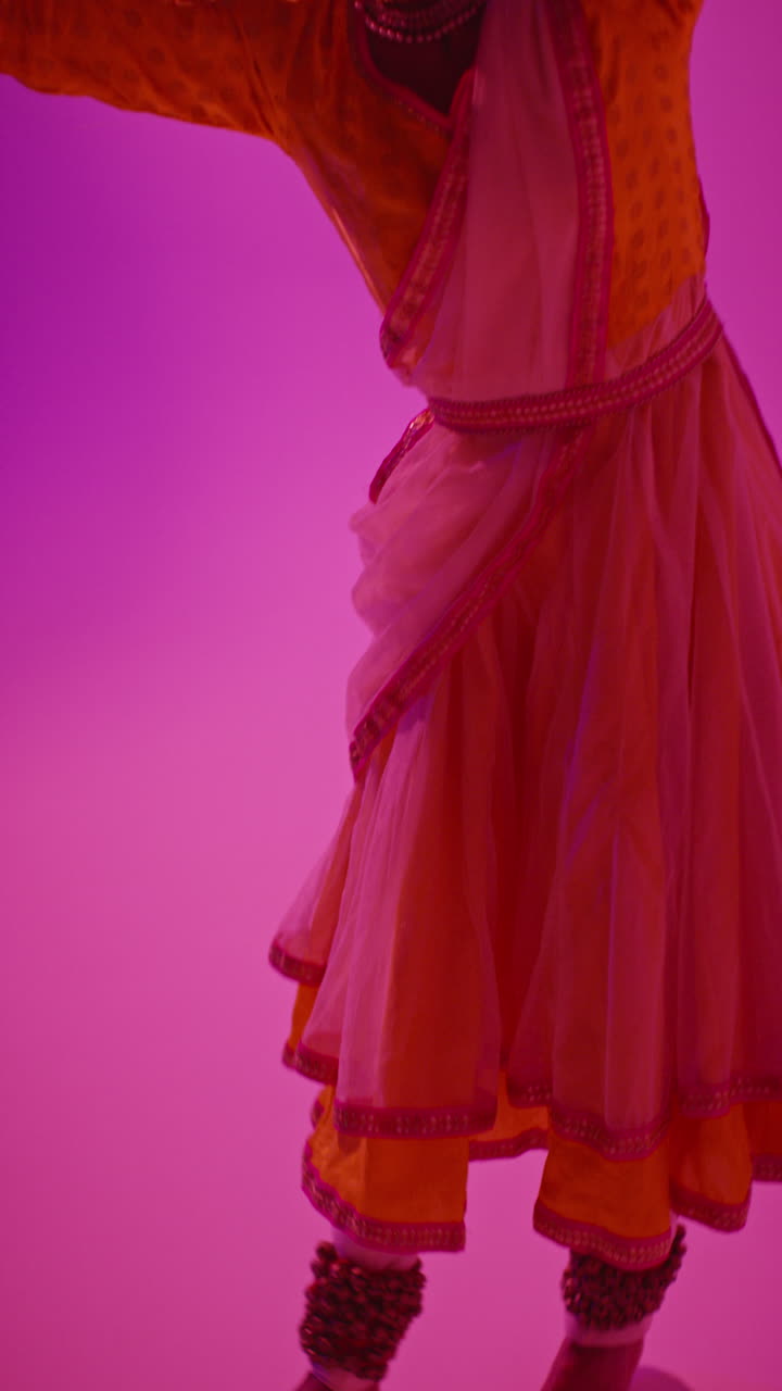 video de estudio vertical de una bailarina de kathak que realiza un baile vestida con el vestido tradicional indio contra un fondo púrpura 3