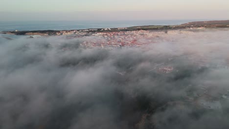 clouds engulfing historic town of lisbon, portugal during sunrise