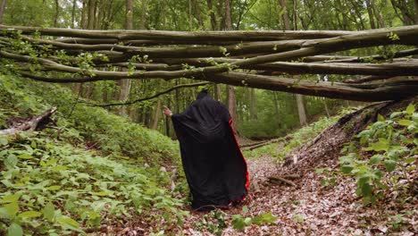 a man in hoodie black cloak is doing a crazy dance moves inside the forest