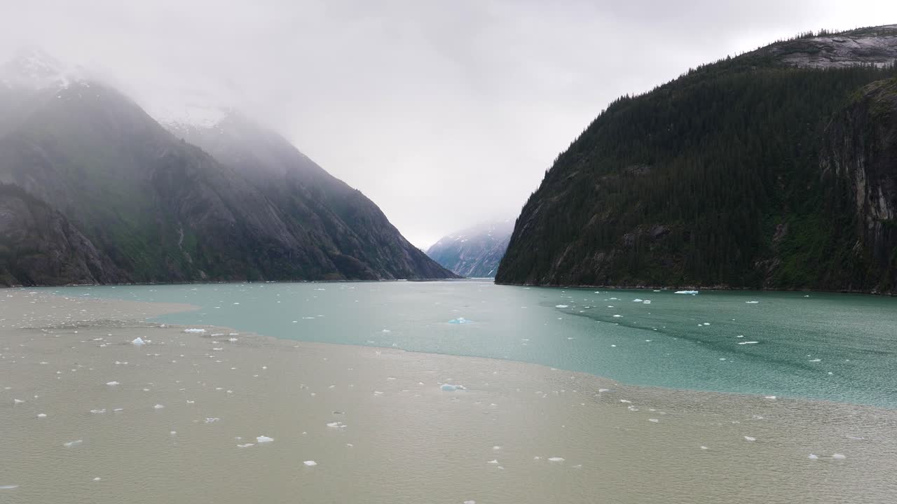 Clear dividing line where the waters of the Endicott Arm fjord meet the waters of Holkham Bay. Dense fog covering the mountains.Entering Endicott Arm fjord, Alaska.