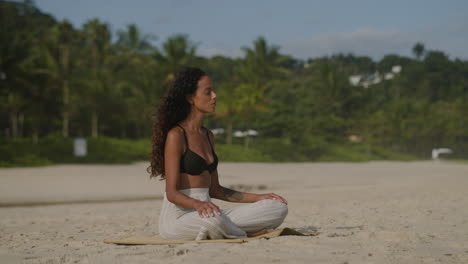 young woman meditating at the beach