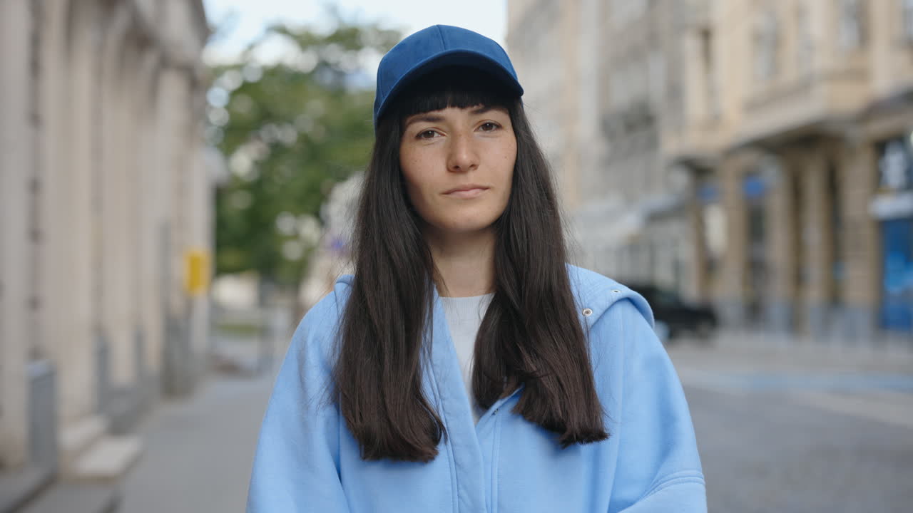 Woman in a blue hoodie and cap on a city street