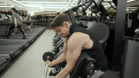 man doing barbell bicep curls on scott bench in modern gym