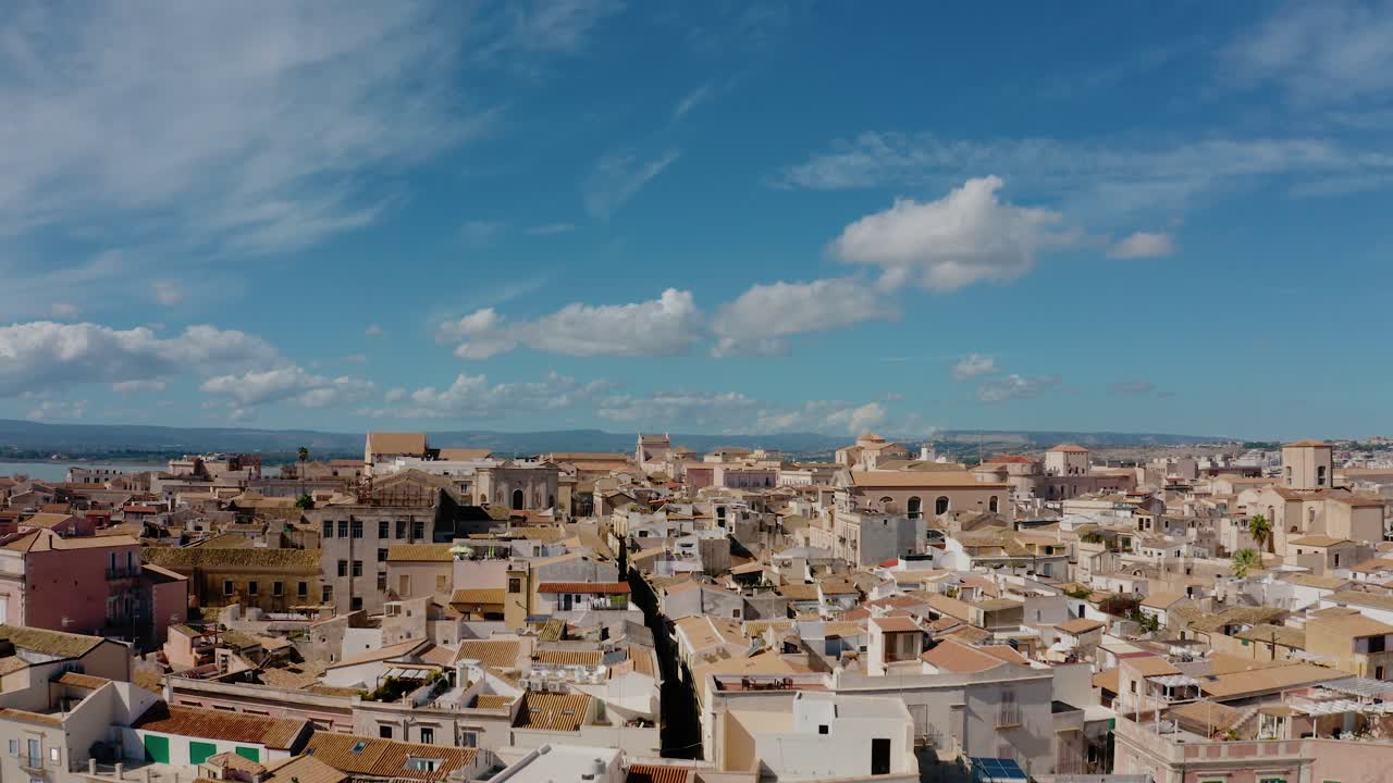 Flying up above rooftops in historic town of Syracuse. Aerial view of Ortigia island buildings. UNESCO world heritage site in Sicily.