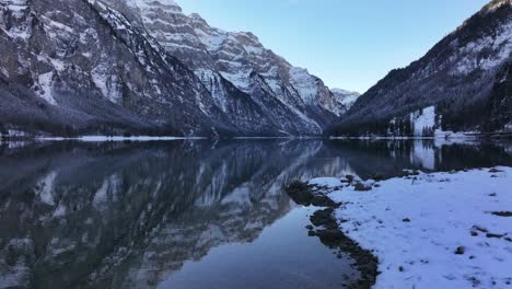 a tranquil winter scene of klöntalersee lake surrounded by snowy swiss alps