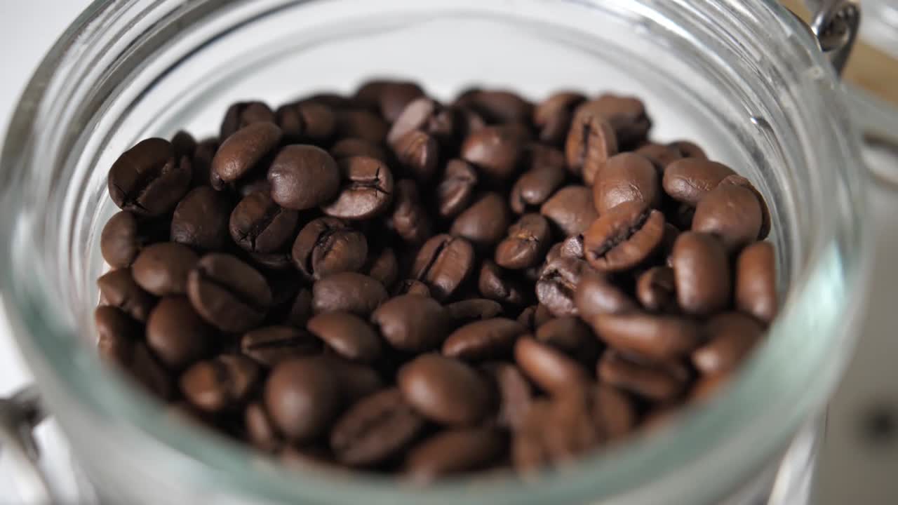 Close up jar full od brown coffee beans. grabbing coffee beans.