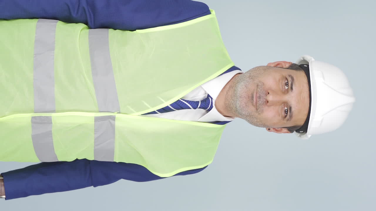 vídeo vertical del ingeniero mira a la cámara y hace una señal de alto.