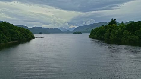 drone aerial footage of derwentwater, keswick, a calm lake with river boats and a stormy sky