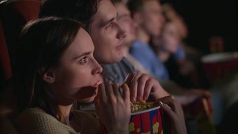 young couple eating popcorn from one box. fiends couple watching movie