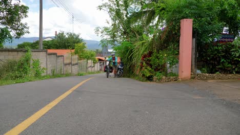 static view of asian young backpacker woman walking with her bicycle through southeast asian rural road