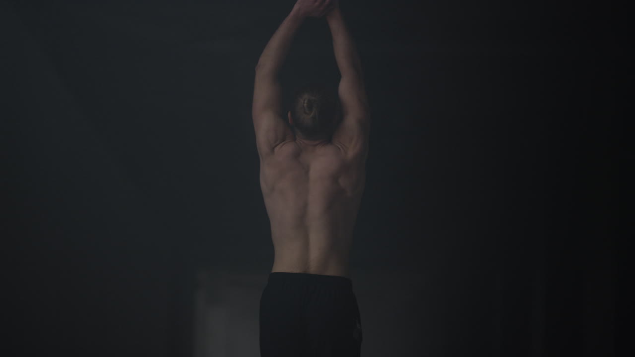 Bodybuilder walking in dark building. Man warming body before intensity training