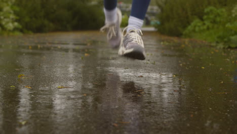 defocused close up of woman exercising keeping fit running in rain towards camera 1