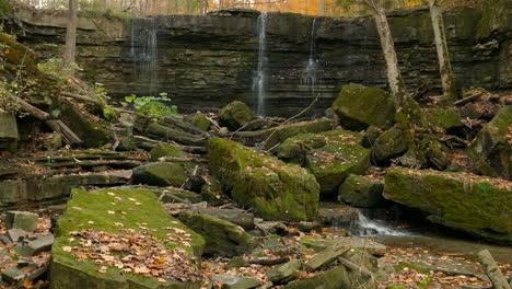 small stream falling into stones covered in moss, majestic forest landscape