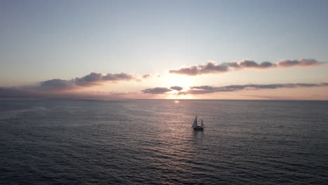 silueta de velero al atardecer: un sereno viaje por el océano con reflejos de sol y olas suaves - imágenes aéreas de drones