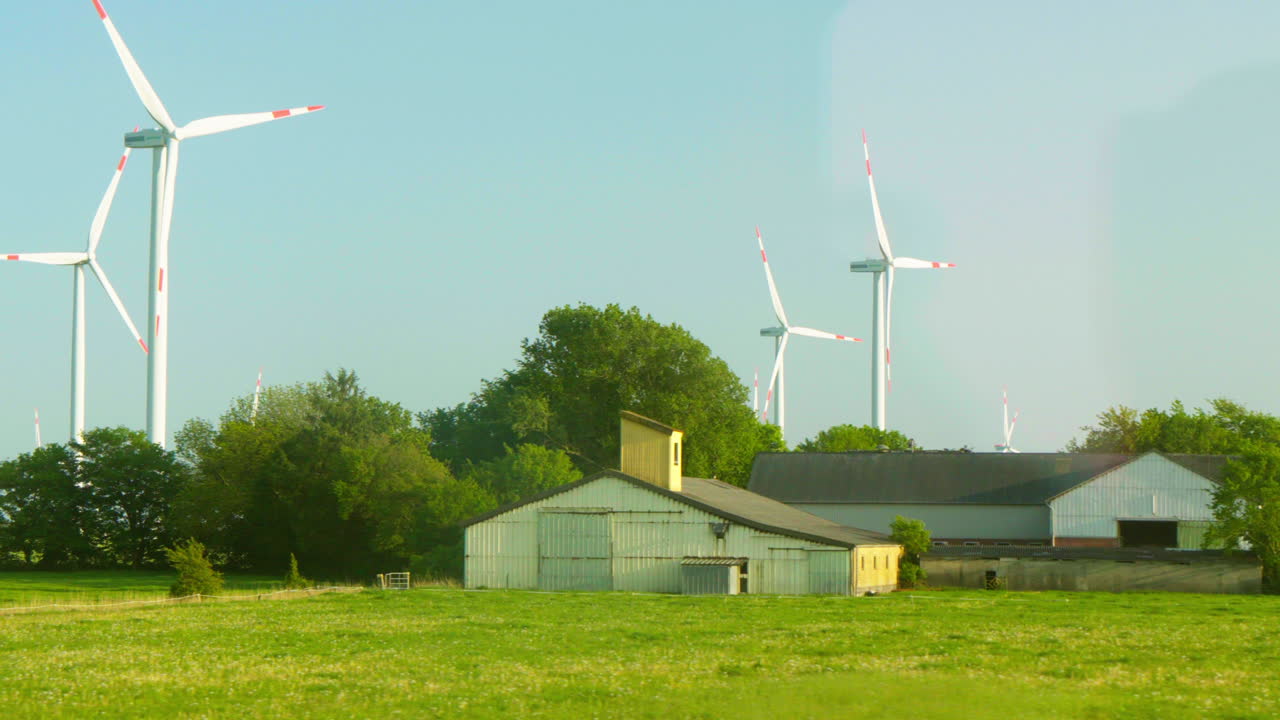 터빈 앞의 농장과 함께 북부 독일의 경치 좋은 풍력 농장을 통과