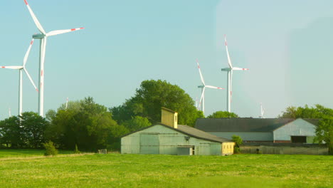 passing by scenic wind farm in north germany with farm in front of turbines