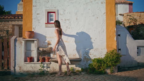 romantic dress lady strolling rural town alone. woman touching old house window