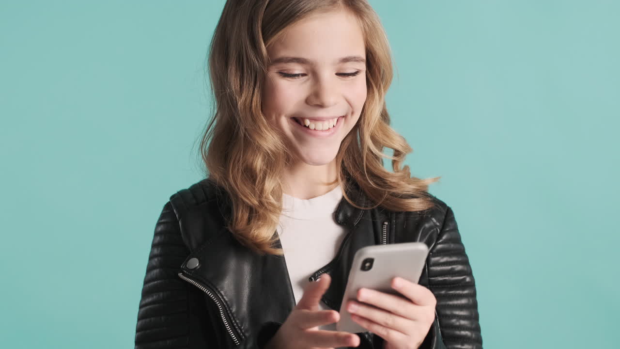Teenage Caucasian girl in leather jacket using her smartphone.