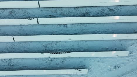 Top-down-drone-shot-over-snowy-solar-panels,-winter-evening-in-Scandinavia