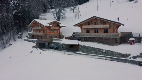 Luftaufnahme-Eines-Autos,-Das-Zu-Einem-Wunderschönen-Chalet-Fährt-Und-In-Einer-Garage-In-Einer-Schneebedeckten-Landschaft-Parkt