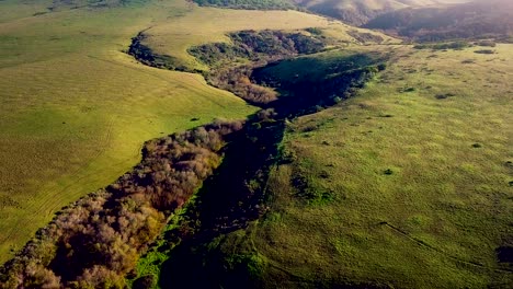 dawn sun pours over california mountains to light rolling green hills