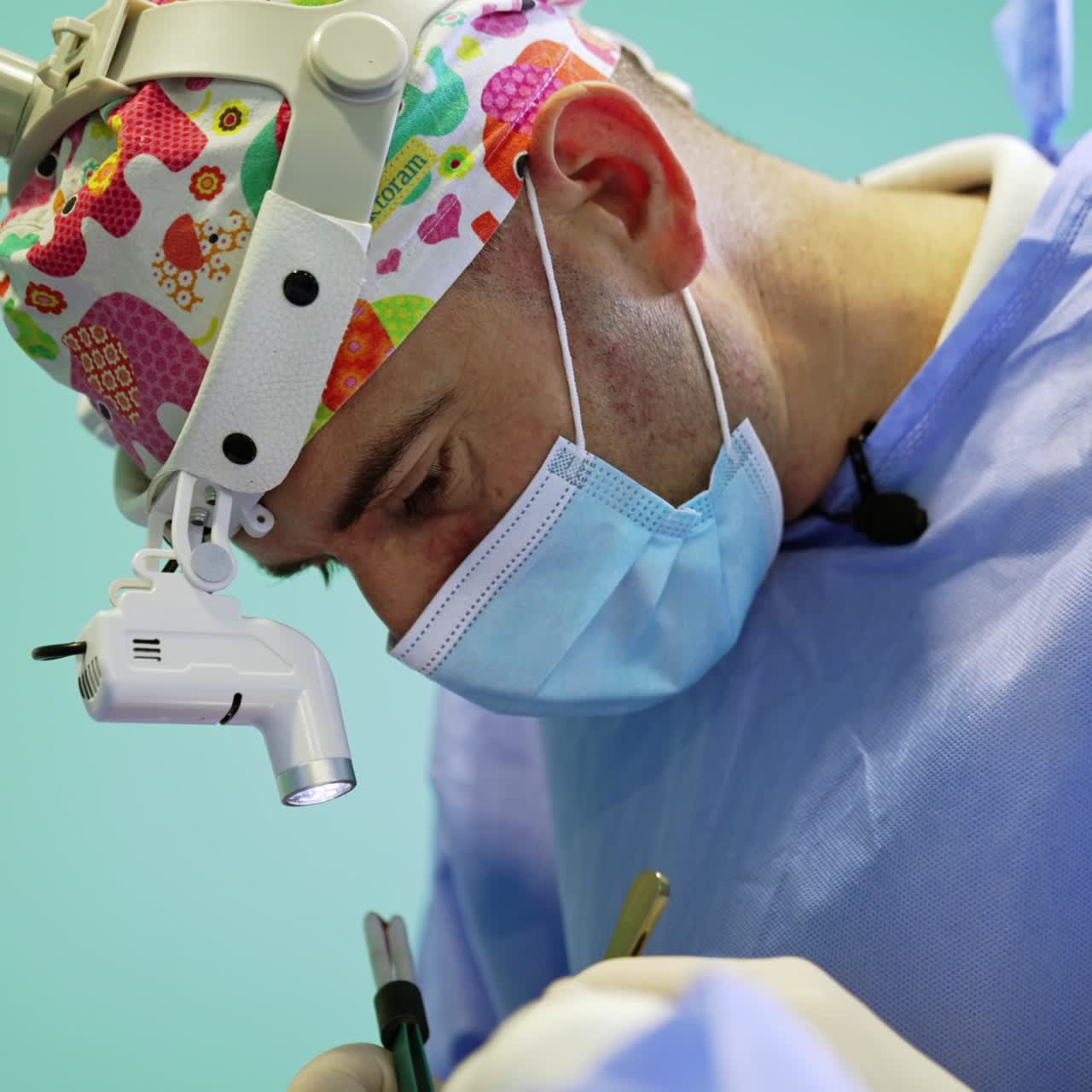 Un chirurgo caucasico utilizza con attenzione uno strumento in metallo e un dispositivo elettrico. Ritratto di un professionista sanitario concentrato sul lavoro