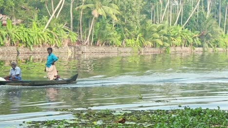 mode of inland water transport , two asian men ride a wooden watercraft motor on a local waterway