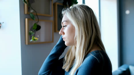 Woman-looking-outside-through-window-at-home-4k