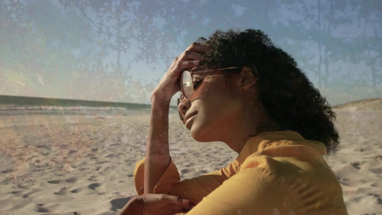 Animazione di un albero sopra una donna afroamericana seduta in spiaggia.