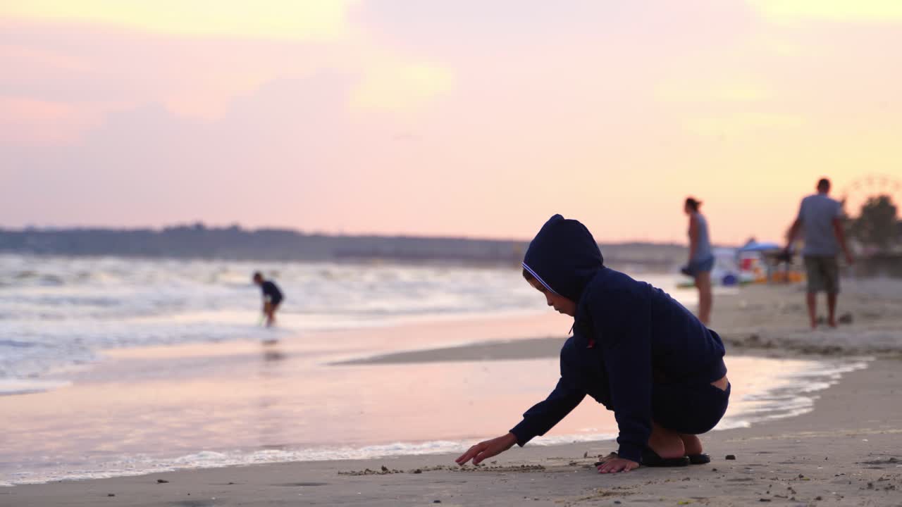 Boy writes words on sand. Little boy writing on the beach sand