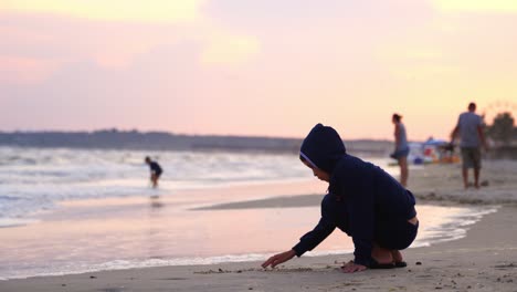 boy writes words on sand. little boy writing on the beach sand