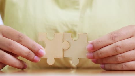 two hands join wooden puzzle pieces symbolizing teamwork and collaboration