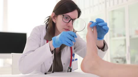 doctor examining patient's foot with magnifying glass