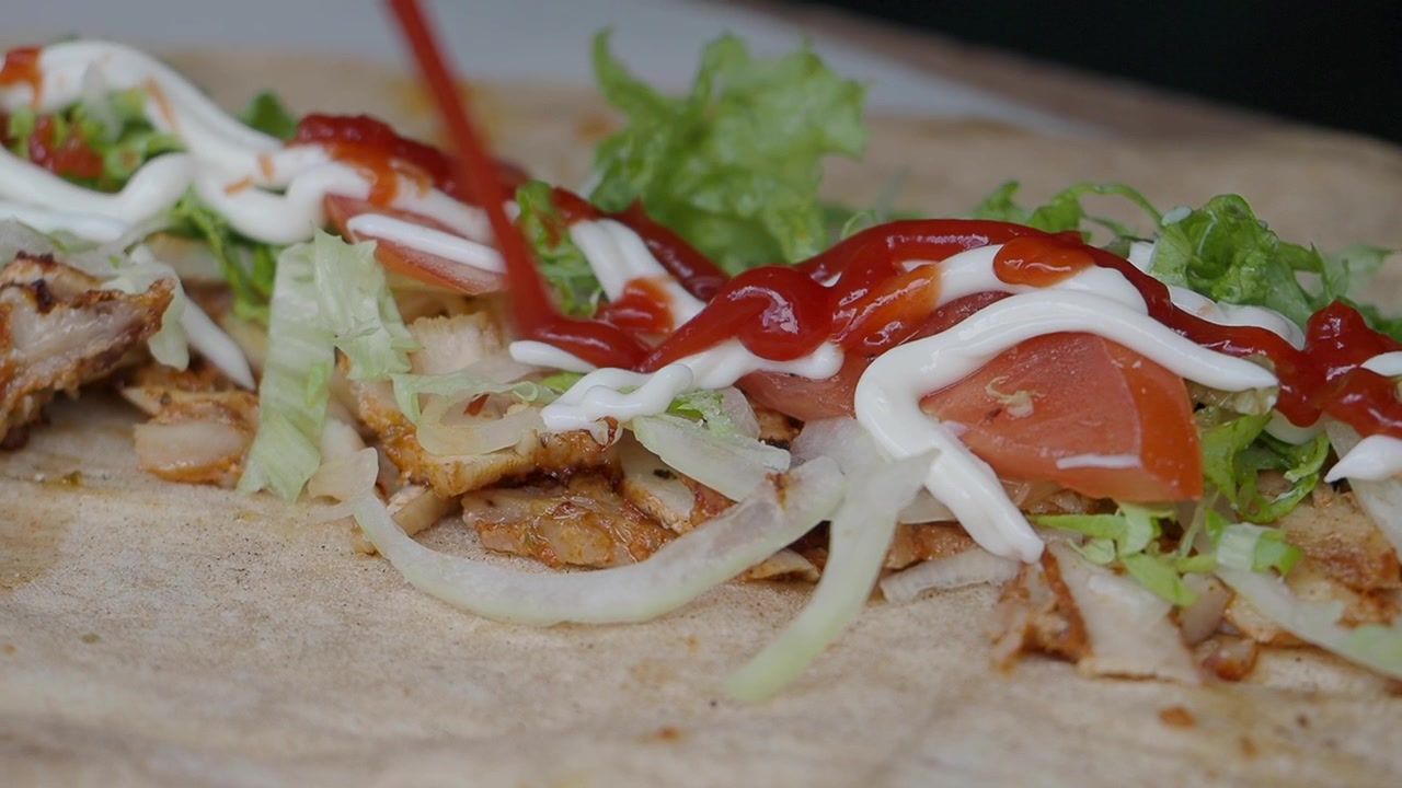Aggiunta di ketchup e maionese a un delizioso wrap di shawarma di pollo